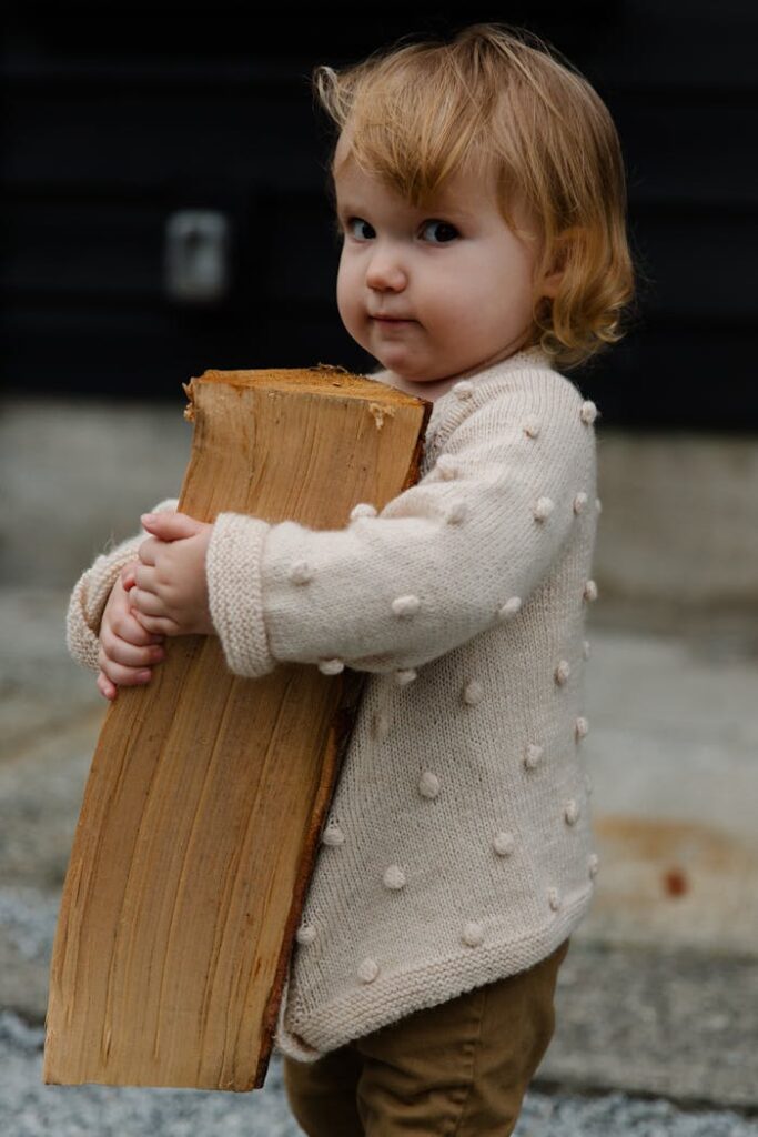 pexels-photo-3849936 Cute toddler holding a log outdoors, wearing a cozy sweater with innocence and charm.